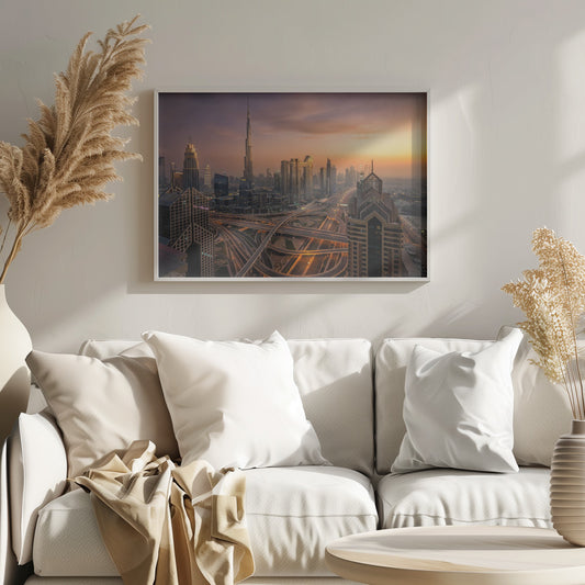 An elevated photograph of the Dubai skyline at sunset, featuring the towering Burj Khalifa against a hazy orange and purple sky. In the foreground, a complex network of illuminated highways and overpasses weaves between modern skyscrapers. Wall Art