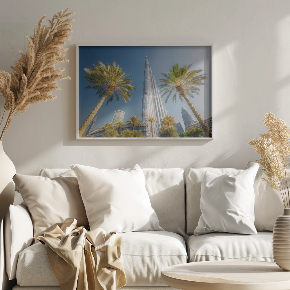 A low-angle photograph looking up at the towering Burj Khalifa skyscraper in Dubai, framed by two large palm trees against a clear, vibrant blue sky. Wall Art