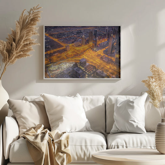 A stunning aerial view of a futuristic city at night, with brilliantly lit highways forming intricate patterns of golden light amidst towering skyscrapers, enclosed in a silver frame. Poster