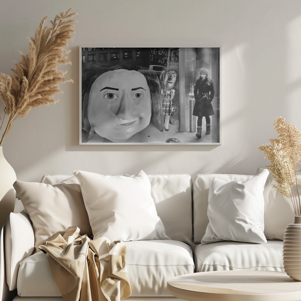 A surreal black and white photograph with a silver frame, featuring a giant, cartoonish head of a historical figure reflected in a window, juxtaposed with a young woman in a winter coat and beanie walking down a city sidewalk. Wall Art