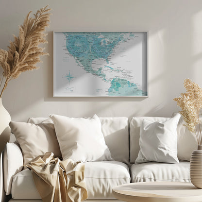 A decorative map of North, Central, and South America in a grey frame. The map has a watercolor texture in shades of blue and teal on a white background, with countries and major cities labeled in a dark font. Print