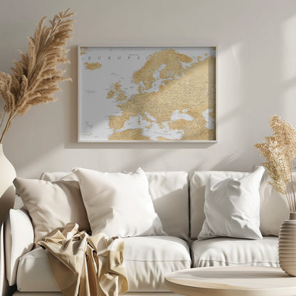 A framed map of Europe featuring golden landmasses on a crisp white background. The map includes country names, major cities, and bodies of water, all presented in a clean, modern font. The artwork is enclosed in a simple, light gray frame. Print