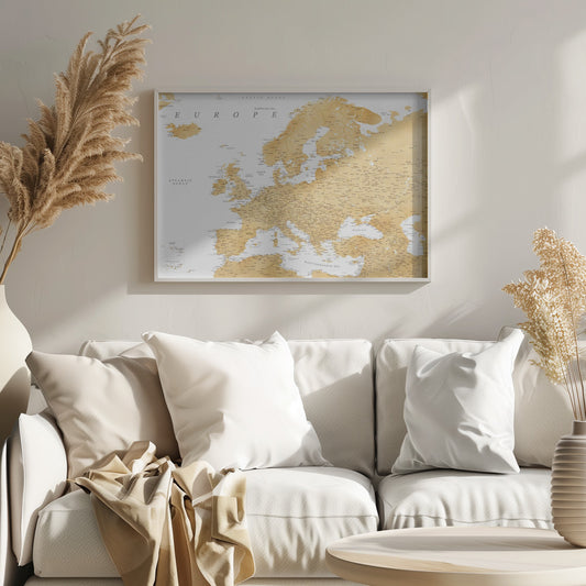 A framed map of Europe featuring golden landmasses on a crisp white background. The map includes country names, major cities, and bodies of water, all presented in a clean, modern font. The artwork is enclosed in a simple, light gray frame. Print