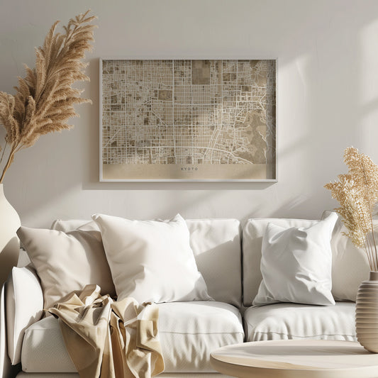 A framed, stylized map of Kyoto, Japan, in shades of brown and beige. The city streets are illustrated as a complex grid of off-white lines against a textured brown background. At the bottom, a solid beige banner contains the text 'KYOTO' and 'JAPAN' in a modern sans-serif font. The artwork is surrounded by a brushed silver frame. Artwork