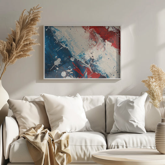 A close-up of an abstract painting in a silver frame, featuring a dynamic composition of red, white, and blue. Thick strokes of paint are splattered and swirled across the canvas, with a large area of deep blue on the left, a bold patch of bright red on the upper right, and a field of off-white in the middle. The piece has a textured, energetic quality. Artwork
