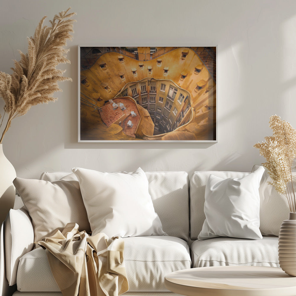 A high-angle photograph looking down into the surreal, undulating inner courtyard of an architectural masterpiece. The warm, golden-ochre walls curve organically, dotted with small, hooded windows, encircling the deep central lightwell that reveals floors of apartments below. Wall Art