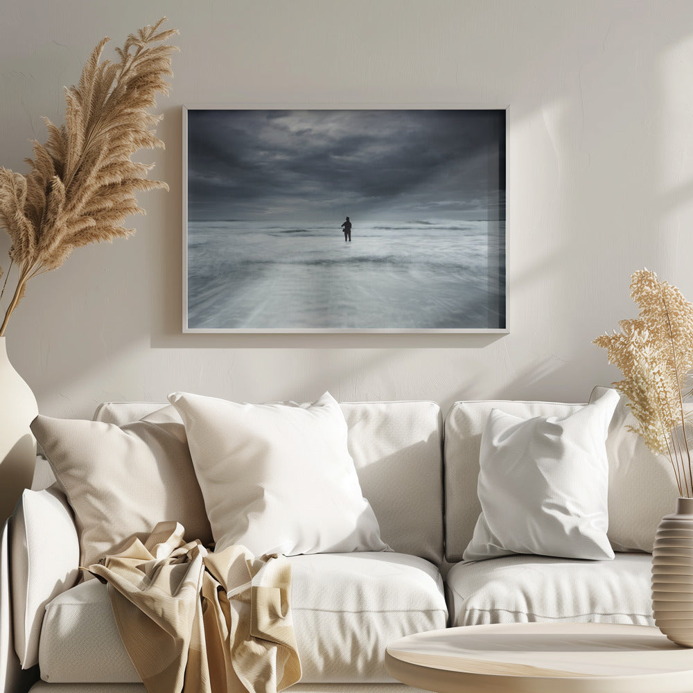 A moody, long-exposure photograph of a silhouetted fisherman standing in the churning white surf of the ocean under a dark, stormy sky, presented in a silver frame. Wall Art