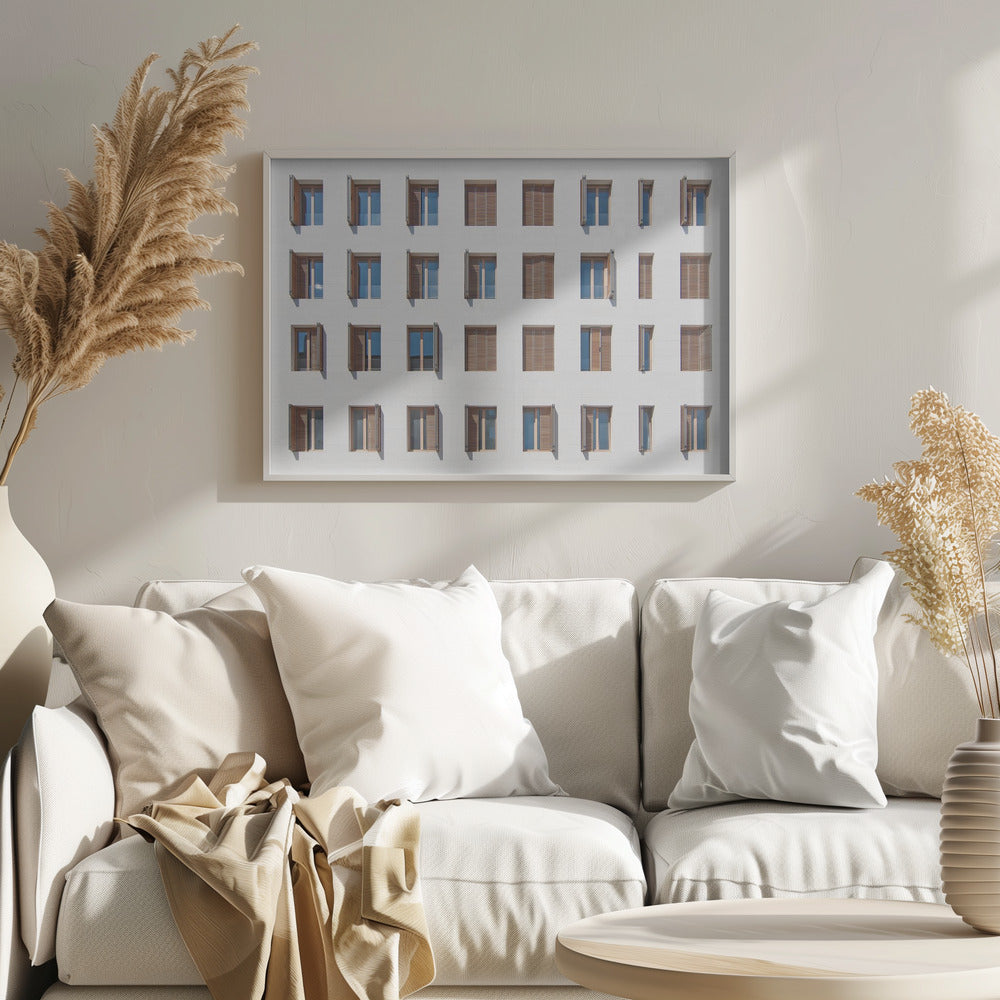 A symmetrical architectural photo of a modern white building facade featuring a grid of twenty-eight windows with wooden louvered shutters, some open and some closed, creating a varied pattern, all within a brushed silver frame. Decor