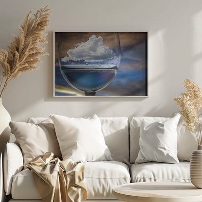 A surreal close-up of a wine glass holding blue liquid and a single white cloud, with water droplets on the glass, set against a blurred background and enclosed in a silver frame. Print