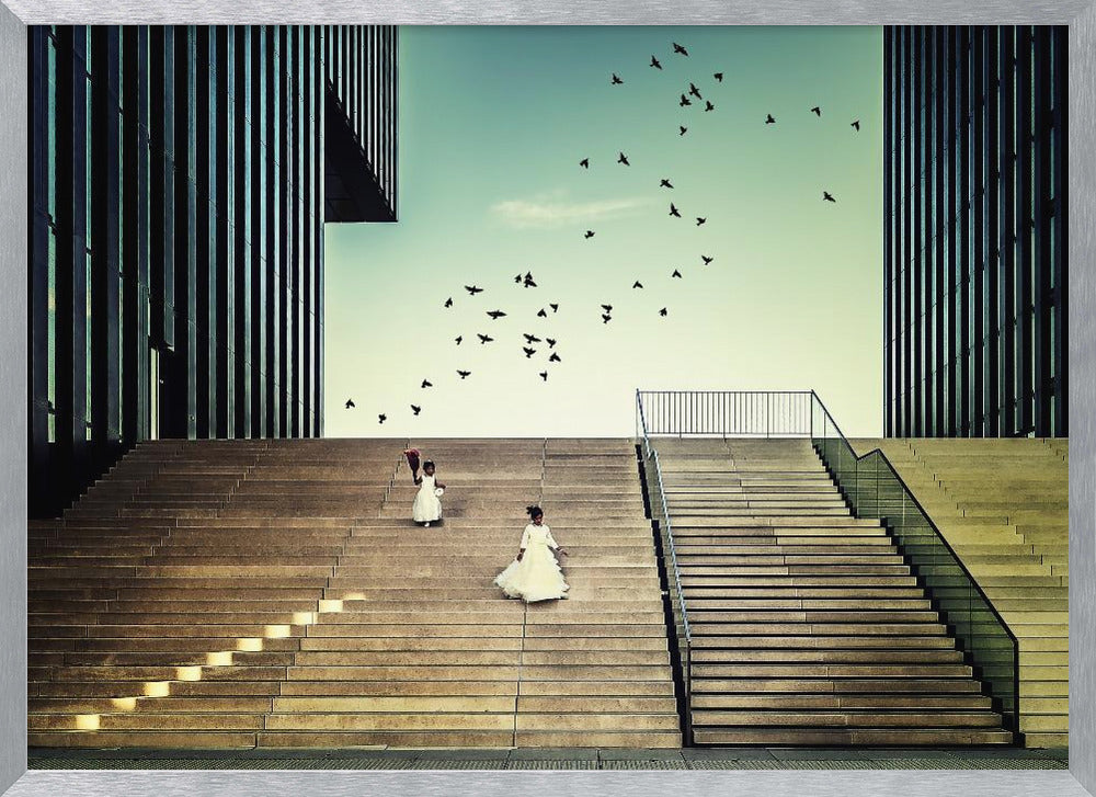 A framed piece of art depicting two young girls in white dresses climbing a vast, modern concrete staircase flanked by two towering, dark buildings. A large flock of birds flies through the teal sky above them, adding a sense of movement to the structured, architectural scene. Poster