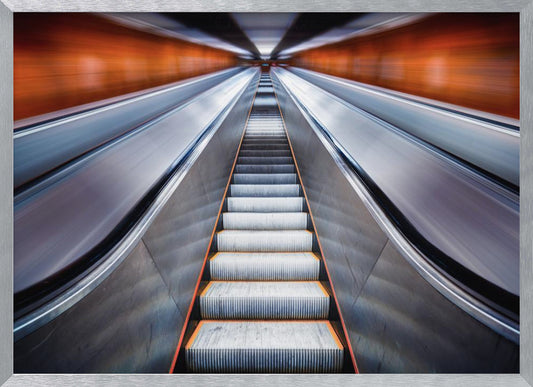 A symmetrical, low-angle photograph looking up a very long escalator, creating a strong sense of perspective towards a vanishing point. The orange walls are motion-blurred, suggesting speed, while the metallic steps in the center remain clear. Decor