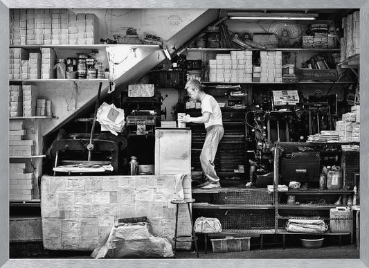 A vintage art print depicting a small, old-fashioned printing shop interior, showcasing antique machinery and a nostalgic atmosphere. Artwork