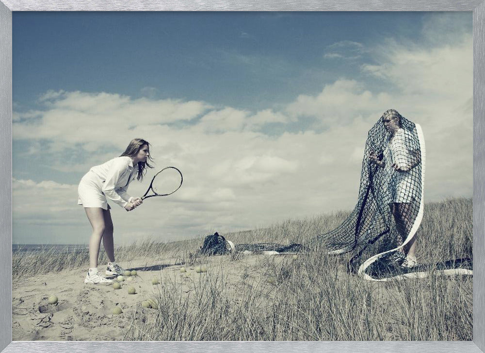 A surreal photograph of two women on a grassy sand dune. One woman is dressed in white tennis attire, bent over and ready to hit a ball with her racket. The other woman stands opposite her, entangled and draped in a large tennis net. The scene is under a cloudy blue sky and has a desaturated, cool-toned color palette, framed in silver. Decor