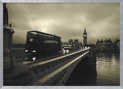 A framed, sepia-toned long-exposure photograph of London. A double-decker bus is shown in motion blur as it crosses Westminster Bridge. In the background, the Big Ben clock tower and the Houses of Parliament are visible against a cloudy sky, with lights reflecting on the wet road and the River Thames. Wall Art