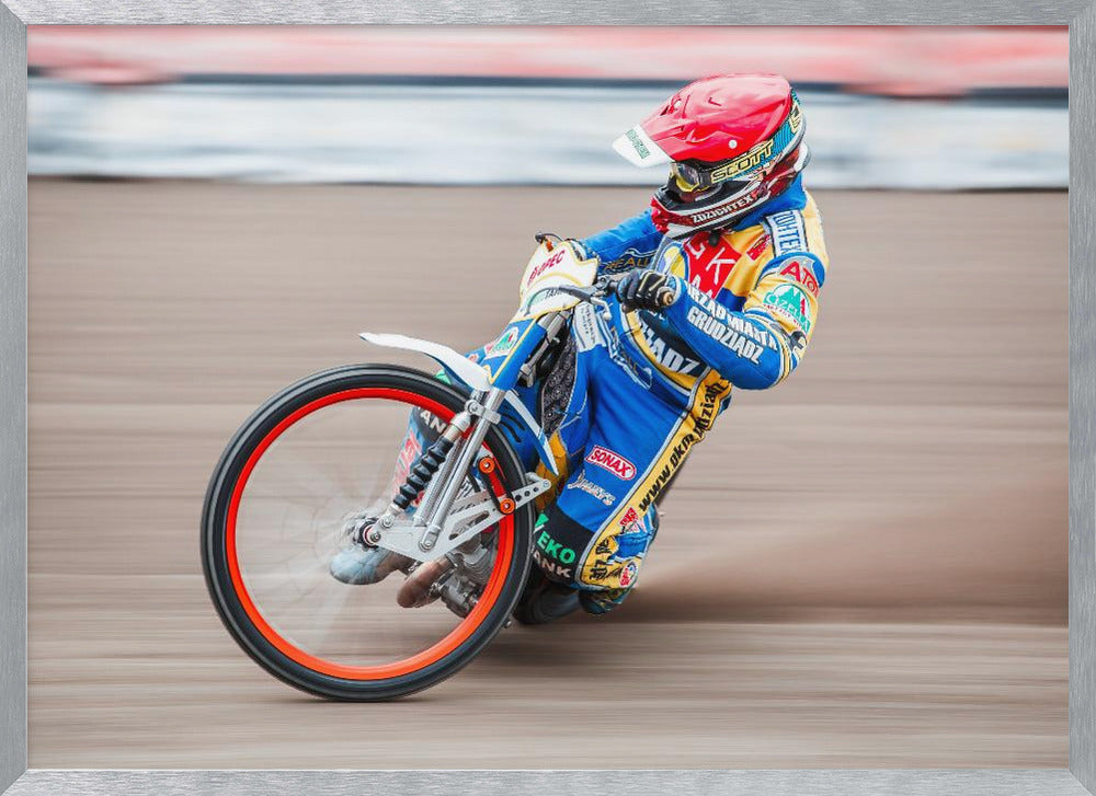 A speedway motorcycle racer in a blue and yellow suit with a red helmet leans sharply into a turn on a dirt track, with motion blur in the background conveying a sense of high speed. Print