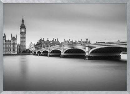 A black and white long-exposure photograph of the Elizabeth Tower (Big Ben) and the Houses of Parliament in London, viewed from across the River Thames. Westminster Bridge stretches across the frame over the smooth, milky water. The image is presented in a silver frame. Artwork