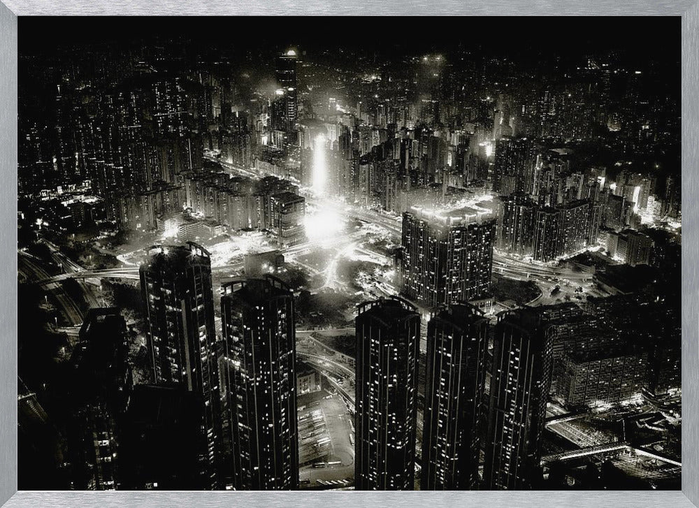 A framed black and white aerial photograph of a dense city at night. The high-angle view captures countless illuminated skyscrapers and winding highways, creating a dramatic and bustling urban landscape. Print