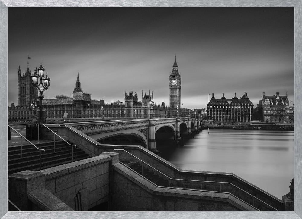 A framed, black and white, long-exposure photograph of the London skyline featuring the Houses of Parliament and the Big Ben clock tower across the River Thames. In the foreground, stone steps lead down towards Westminster Bridge, and the water of the river is smooth and reflective under a dark, cloudy sky. Print