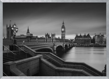 A framed, black and white, long-exposure photograph of the London skyline featuring the Houses of Parliament and the Big Ben clock tower across the River Thames. In the foreground, stone steps lead down towards Westminster Bridge, and the water of the river is smooth and reflective under a dark, cloudy sky. Print