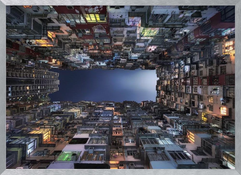 A striking low-angle photograph looking up from a narrow courtyard at the night sky, completely framed by towering, densely packed, and weathered apartment buildings with glowing windows, creating a sense of urban enclosure. Decor
