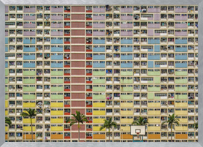 A symmetrical, frontal photograph of the colorful Choi Hung Estate in Hong Kong, featuring a massive grid of apartments with balconies painted in a rainbow of pastel colors including purple, blue, green, yellow, and orange. Palm trees and a basketball court are visible at the base of the building, which is enclosed in a silver frame. Wall Art