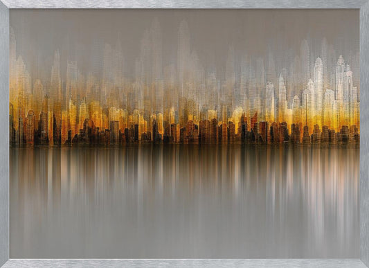 An abstract painting of a city skyline at sunset or sunrise, with buildings glowing in shades of gold, orange, and brown. The hazy, gray sky shows faint outlines of taller buildings in the background. The city is reflected in the water below, with the colors stretched into long, vertical streaks that blend into the gray foreground. The entire piece is enclosed in a simple silver frame. Wall Art