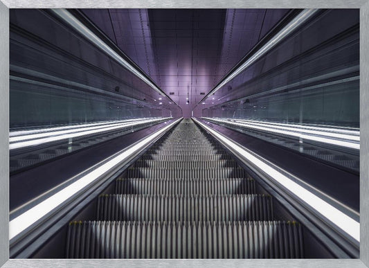 A symmetrical, first-person view looking down a long, empty escalator in a modern subway station, with bright white lights lining the handrails and a purple glow on the ceiling, creating a futuristic and infinite perspective. Wall Art
