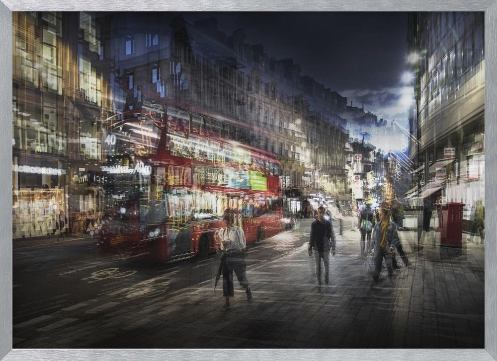 A long-exposure, artistic photograph of a busy London street at night. The motion of a red double-decker bus and pedestrians creates a blurred, ghost-like effect, capturing the vibrant energy of the city. The scene is illuminated by streetlights and building windows, all set within a silver frame. Artwork