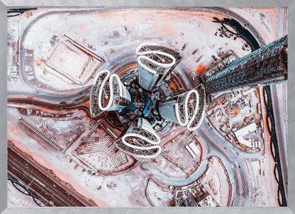 A dizzying top-down aerial photograph of five futuristic, petal-shaped skyscrapers surrounding a central turquoise pool. The surrounding urban landscape is a mix of dusty pink construction sites and curving roads, creating a surreal and abstract cityscape. Wall Art