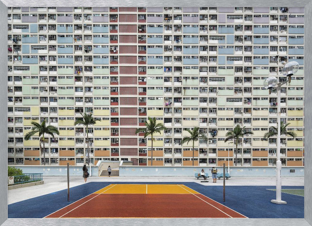 A wide, symmetrical photograph of the colorful Choi Hung Estate apartment building in Hong Kong, featuring a facade with a repeating pattern of pastel blue, green, yellow, and orange blocks. In front of the building is a vibrant basketball court painted in bold sections of blue, red, and yellow, with several palm trees lining the courtyard. Print