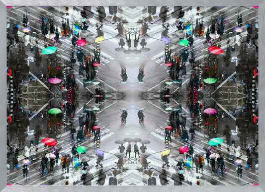 A symmetrical, kaleidoscopic abstract artwork created from an aerial view of a rainy city intersection. The mostly black and white image features pops of vibrant color from numerous umbrellas held by pedestrians crossing the street, all framed in a textured silver border. Artwork