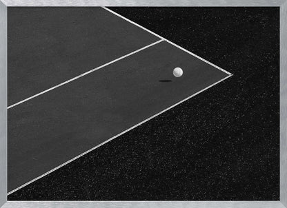 A minimalist black and white overhead photograph of a white ball resting in the corner of a dark tennis or paddle court. The composition focuses on the strong geometric angles created by the white boundary lines against the dark, textured asphalt, all within a silver frame. Artwork