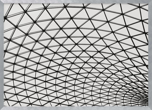 A framed, black and white photograph of a modern architectural dome ceiling. The image is a close-up, looking up at the intricate metal framework that creates a repeating pattern of triangles against the bright glass panels. Poster