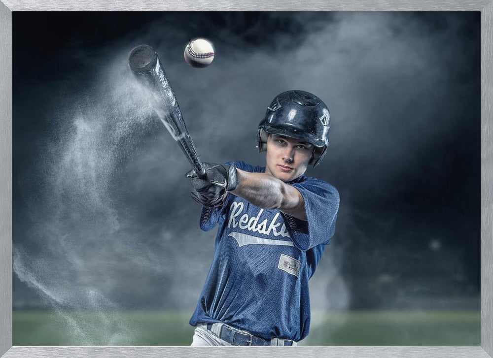 A dramatic, framed portrait of a young baseball player in a blue jersey and helmet, captured in the moment of hitting a baseball, with a cloud of dust exploding from the bat against a dark, smoky background. Poster