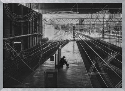 A framed, high-contrast black and white photograph of a person sitting alone on a deserted train platform, with tracks stretching into the distance. The entire scene is overlaid with frenetic white scribbles, creating an abstract and moody effect. Artwork