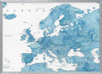 A framed map of Europe with a blue watercolor texture. The land is depicted in various shades of blue, while the oceans are white. Countries, cities, and bodies of water are labeled in black text. The map is housed in a simple, light gray frame. Poster