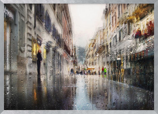 An impressionistic painting of a city street on a rainy day, viewed as if through a window covered in water droplets. The scene is blurred and atmospheric, with the wet pavement reflecting the muted colors of the buildings and distant figures. The artwork is presented in a silver frame. Decor