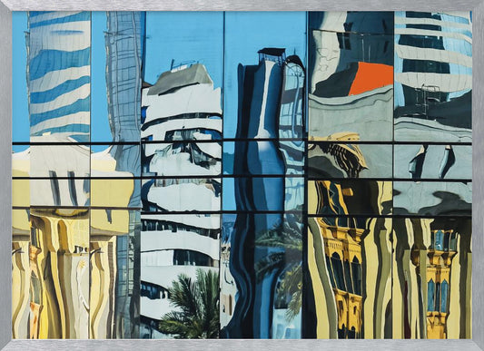 A framed abstract artwork showing a collage of distorted cityscape reflections in a grid of glass window panes. The reflections mix modern blue and white skyscrapers against a clear blue sky with older, golden-yellow buildings, creating a wavy and fragmented visual effect. Wall Art