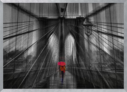A motion-blurred, black and white photo of the Brooklyn Bridge with a person holding a bright red umbrella walking down the center. The selective color makes the red umbrella the focal point against the dramatic, almost abstract lines of the bridge's cables and arches on a wet, reflective walkway. The image is presented in a silver frame. Wall Art