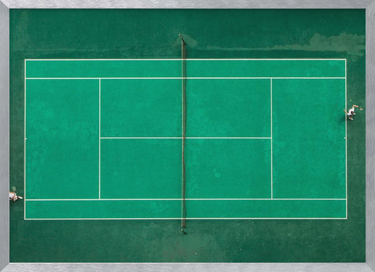 An aerial top-down photograph of a vibrant green tennis court with two players in the middle of a game, one on the far left and the other on the far right, all enclosed within a brushed silver frame. Print