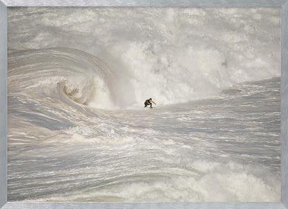 A framed photograph of a lone surfer dwarfed by a massive, powerful ocean wave. The water is a churning mass of white foam and spray, and the surfer is navigating the enormous swell. Print