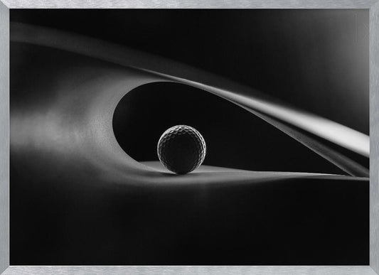An artistic black and white photograph of a golf ball resting inside the gentle curve of a dark, abstract shape, creating a minimalist and dramatic composition with strong light and shadows. Poster