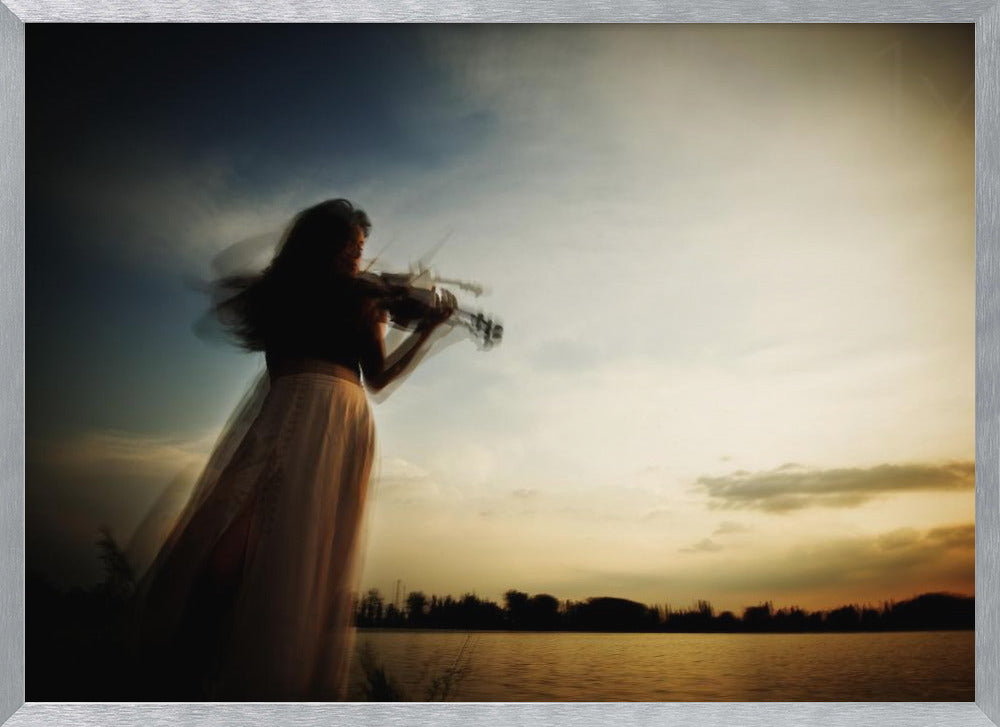 An artistic, framed photograph with motion blur capturing the silhouette of a woman in a long flowing skirt playing the violin by a lake against a dramatic sunset sky. Poster
