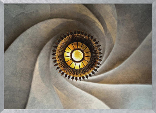 A low-angle, centered photograph looking up at an ornate, golden sunburst chandelier hanging from the vortex of a swirling, textured cream-colored ceiling, enclosed in a silver frame. Poster