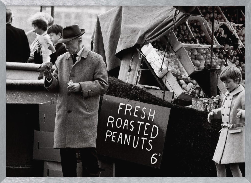 A vintage black and white photograph of an elderly man in a fedora and overcoat feeding a pigeon from his hand at an outdoor market. A sign for 'FRESH ROASTED PEANUTS' is visible next to him, and a young boy in a coat watches nearby. Wall Art