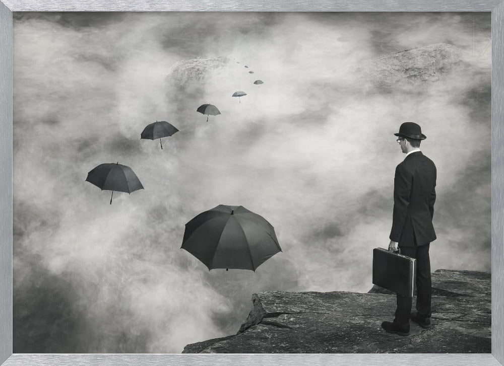 A surreal black and white photograph of a man in a suit and bowler hat holding a briefcase, standing on a cliff edge. He gazes into a foggy expanse where a path of floating black umbrellas leads into the misty distance. Decor