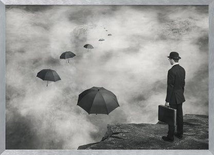 A surreal black and white photograph of a man in a suit and bowler hat holding a briefcase, standing on a cliff edge. He gazes into a foggy expanse where a path of floating black umbrellas leads into the misty distance. Decor