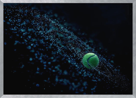A high-speed photograph captures a spinning green tennis ball against a black background, with a dramatic spray of blue-lit water droplets flying off it in a cosmic-like spiral. Artwork