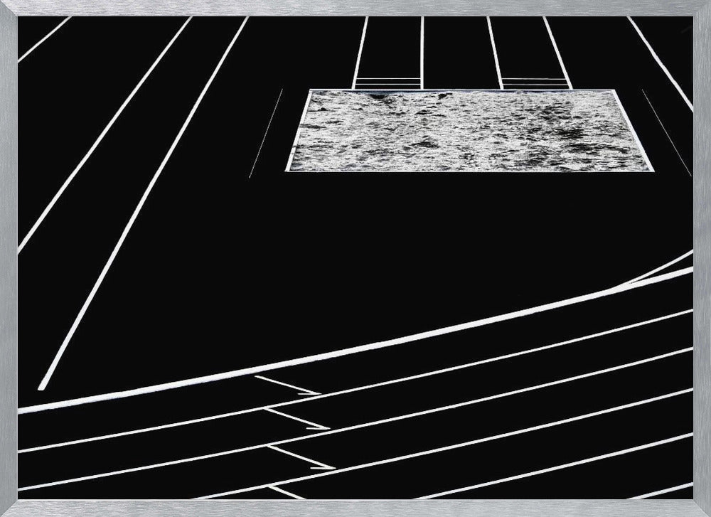 A high-contrast, black and white abstract artwork depicting a running track from an elevated perspective. Stark white lines representing lanes curve across a solid black background. In the upper portion, a rectangular shape filled with a textured, water-like pattern replaces a typical sand pit. The entire piece is presented within a silver frame. Print