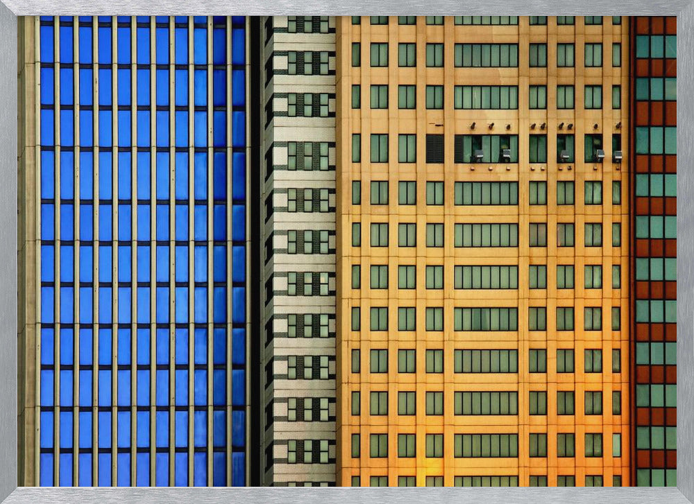 An abstract architectural photograph showing the colorful gridded facades of three adjacent skyscrapers, featuring a blue-windowed building, a white building, and a yellow building, all contained within a silver frame. Wall Art